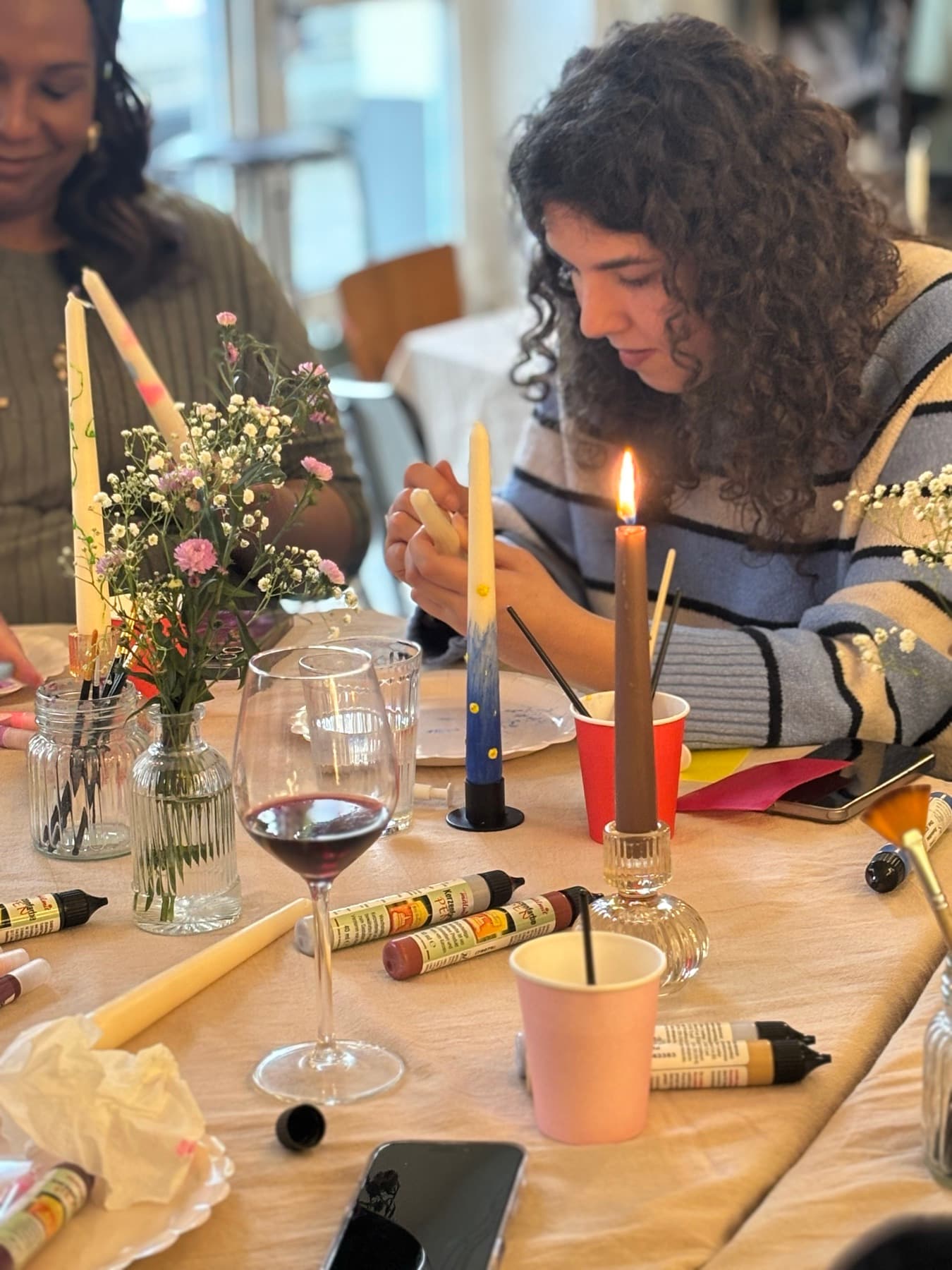 Guests decorating candles at a warmly lit workshop table